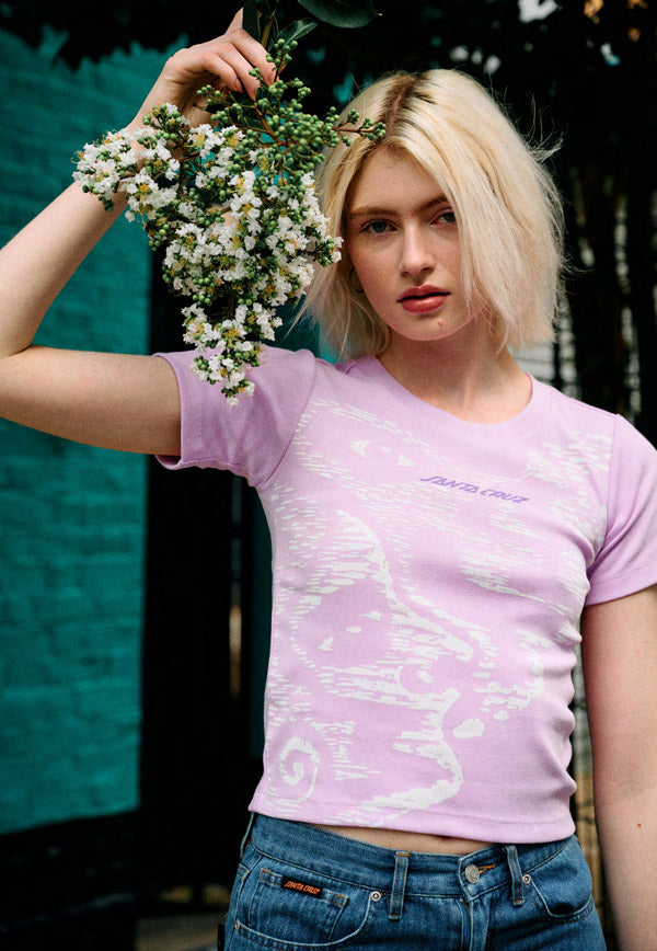 Woman holding a floral wreath wearing a pink lavender Santa Cruz Carved t-shirt with a graphic design.