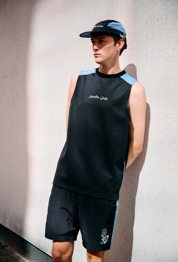 Man wearing a black Santa Cruz artifical scribble vest and shorts with blue accents against a plain background
