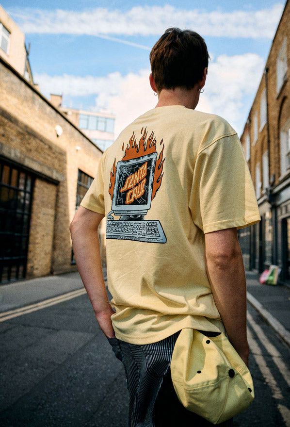 Man wearing a custard Santa Cruz Self Destruct t-shirt with a graphic design on the back, standing on a street.