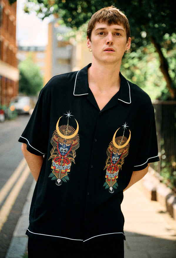 Man wearing a black Santa Cruz Winkowski Samurai Souvenir shirt in an urban setting.