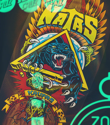 A Santa Cruz skateboard shaped deck with a colorful graphic design on a dark background.