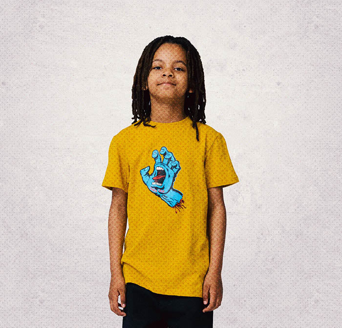 Child wearing a yellow Santa Cruz t-shirt with a screaming hand graphic on a light gray background