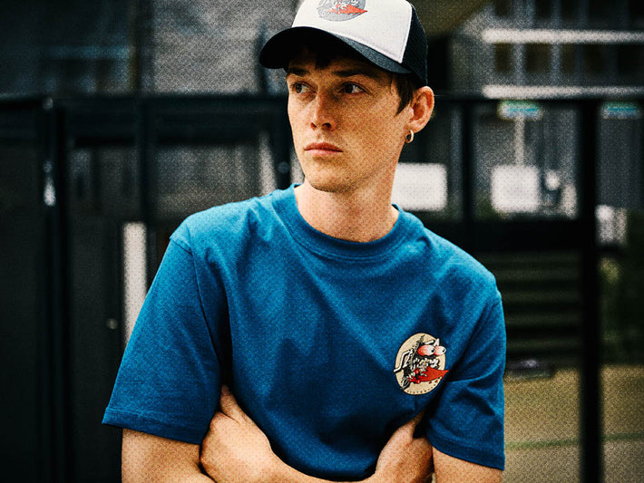 Man wearing a blue Santa Cruz Meek Slasher t-shirt, standing against a blurred background.