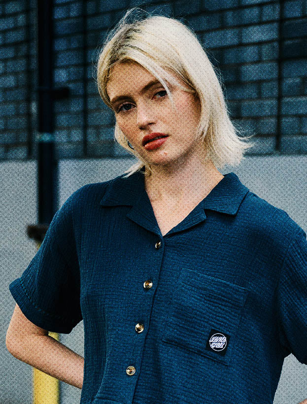 Woman wearing a blue textured Santa Cruz shirt against a dark backdrop.