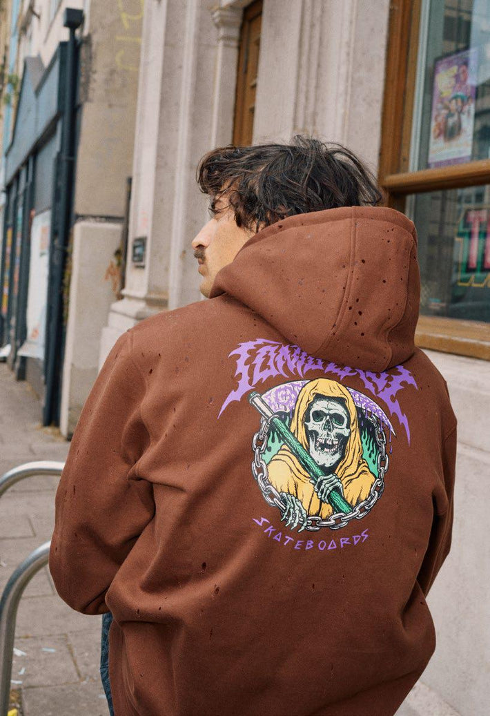 Person wearing a coffee Santa Cruz hoodie with a Out of Time graphic design on the back, standing on a street.